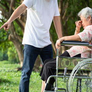 A man pointing to an elderly woman in a wheelchair, highlighting a potential case of elder abuse. - Preston Law Group, P.C