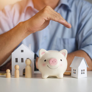 Man holding piggy bank with house and family model on table, symbolizing financial planning for Tax Liability - Preston Law Group